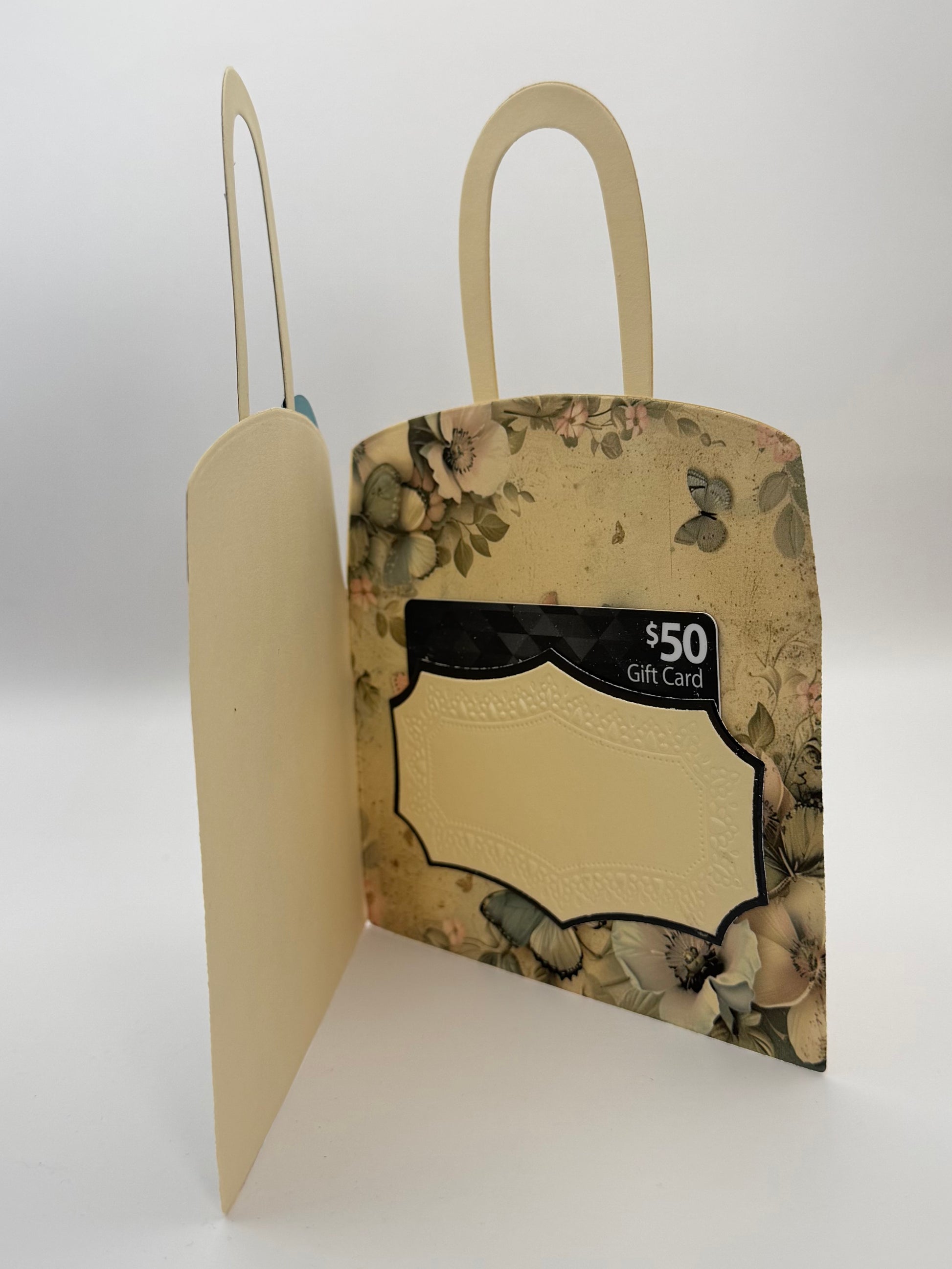A vintage-style gift card holder in the shape of a tote bag, featuring a floral patterned exterior and a cream-colored interior with a card slot.