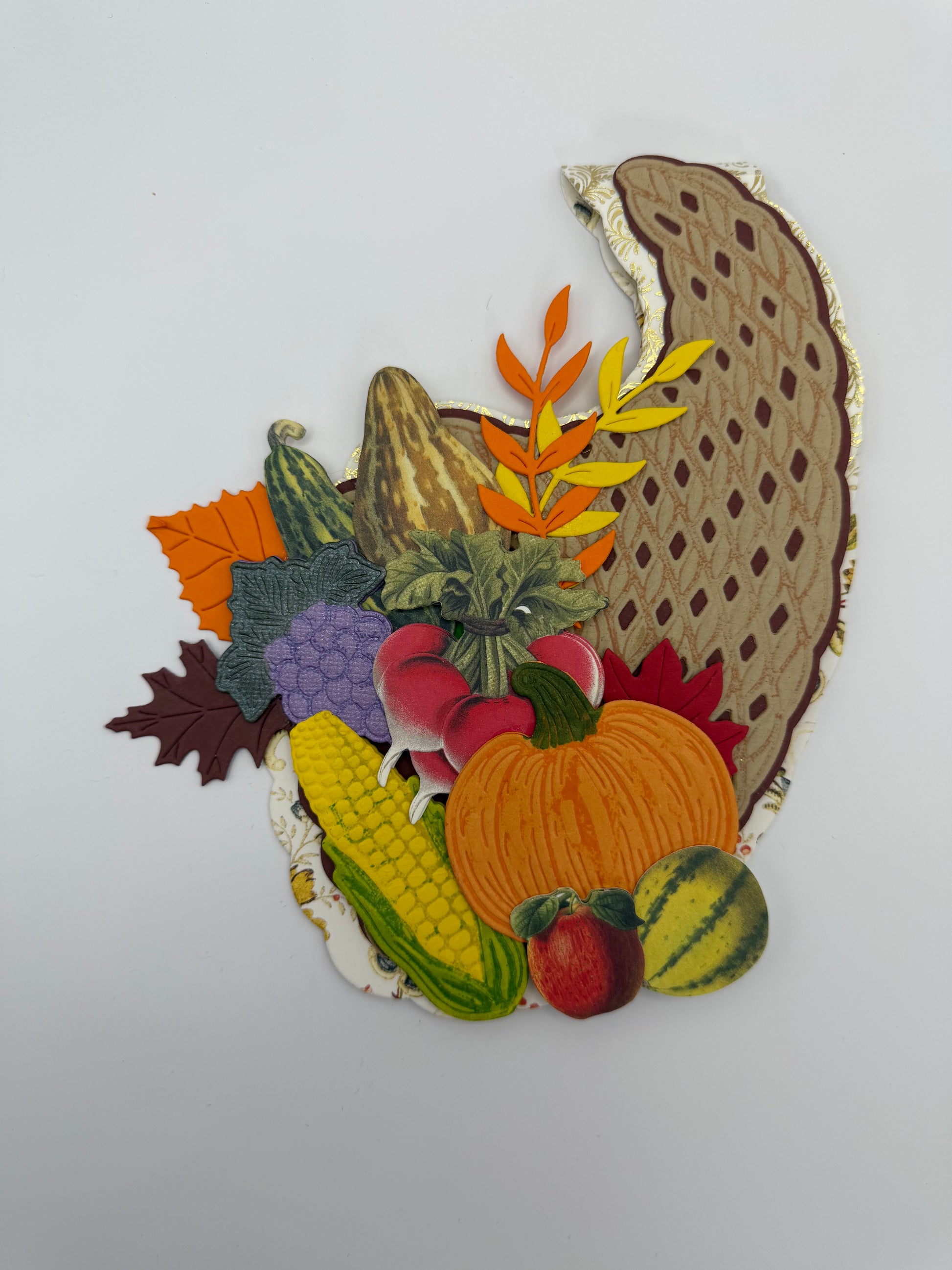 A decorative autumn-themed patch or applique featuring a pie crust outline with layered paper elements including a pumpkin, corn, grapes, leaves, and small fruits on a white background.